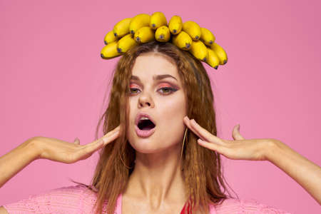 Woman with bananas wavy hair fruits lifestyle bright makeup pink background