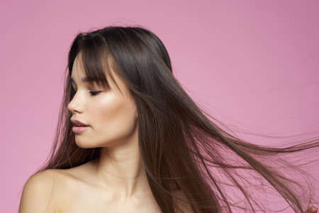 Pretty brunette naked shoulders clear skin pink background
