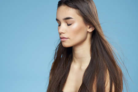 pretty brunette naked shoulders long hair skin care blue backgroundの写真素材