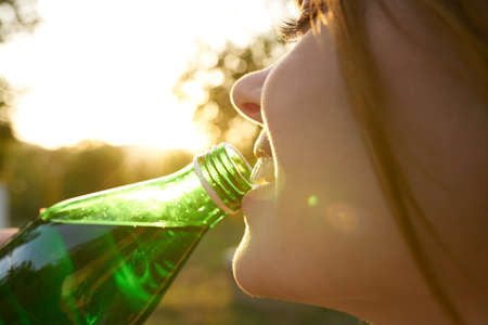 woman with bottle of water in the river close-up summer trees sun natureの写真素材
