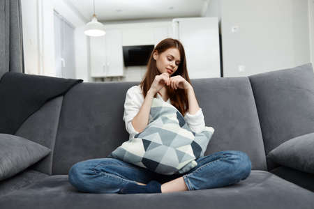 woman at home on the sofa with a pillow in her hands comfortable apartment