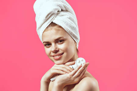 attractive woman with towel on head face massage relaxation pink backgroundの写真素材
