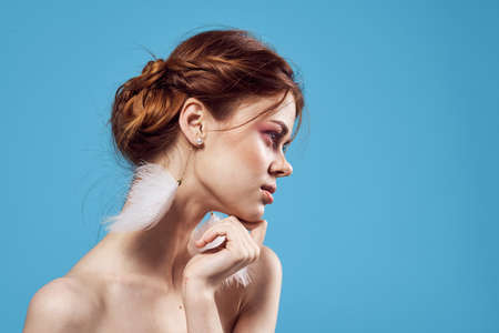 cheerful woman bare shoulders fluffy earrings jewelry pure leather blue backgroundの写真素材