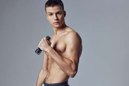 athletic man with dumbbells in hands exercises on the muscles of the arms