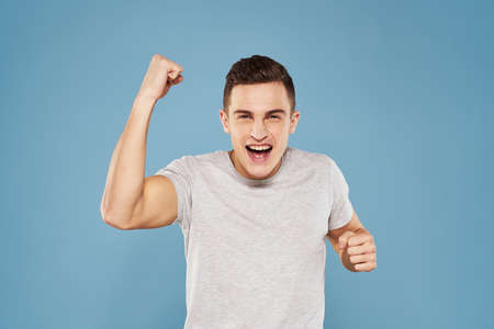 cheerful man in a white t-shirt gesturing with his hands emotions blue backgroundの写真素材