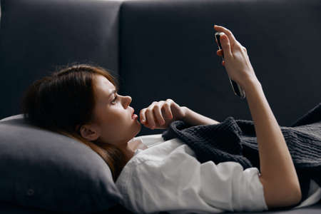 portrait of pretty woman with mobile phone on sofa cropped view