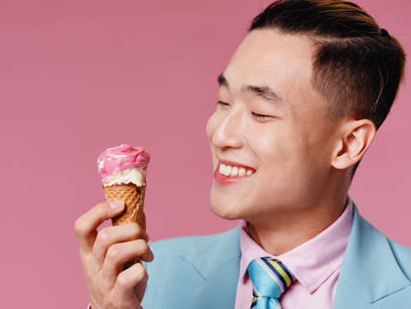 Happy guy in a classic suit and ice cream in a cone pink backgroundの写真素材