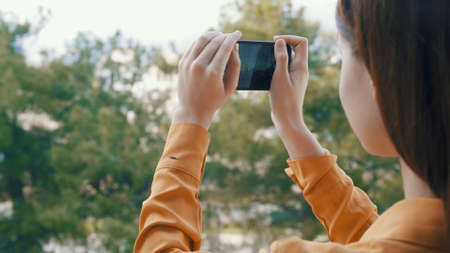 woman outdoors with a phone in her hands taking pictures of nature panorama restの写真素材