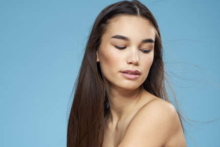 pretty brunette naked shoulders long hair skin care blue backgroundの写真素材