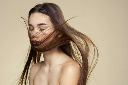 Pretty woman naked shoulders cosmetics clean skin hair care beige backgroundの写真素材