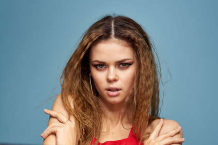 Beautiful woman with wavy hair bright makeup red t shirt lifestyle blue background modelの写真素材