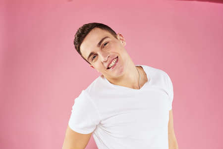 A man in a white t-shirt gestures with his hands emotions pink background studio cropped viewの写真素材