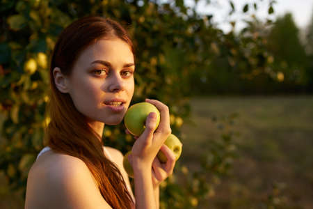 happy woman with apples in her hands in nature Green grass trees Summer sunの写真素材