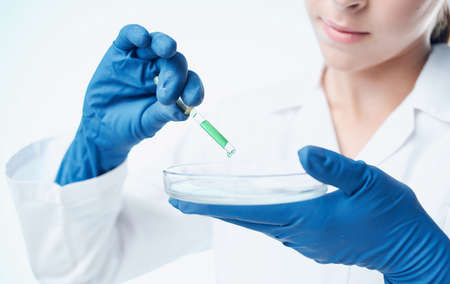 doctor in medical gloves and glasses holds a flask with liquid laboratory chemical elementの写真素材