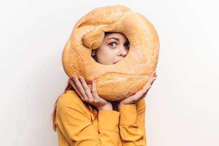 flour product round loaf of bread and emotional woman in a yellow shirt on a light background