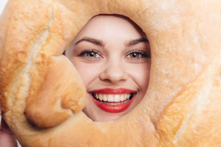happy woman with round loaf of bread in front of face bright makeup emotions funの写真素材
