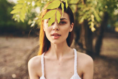 pretty woman in white dress outdoors in the garden and green leaves of treesの写真素材