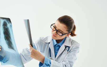 doctor woman examining chest x-ray on light background cropped view
