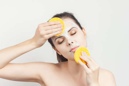 brunette with bare shoulders face mask sponges in handsの写真素材
