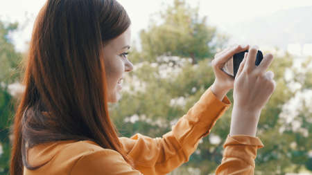 woman outdoors with a phone in her hands taking pictures of nature panorama rest