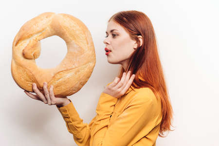 woman holding a round loaf in her hands on a light background in a yellow shirt cropped viewの写真素材