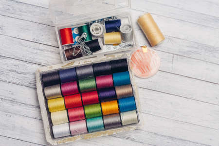 ball of multicolored threads in a box and sewing supplies needles and pins on a wooden tableの写真素材