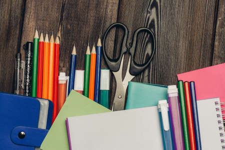 stationery multicolored pencils paper scissors markers on wooden tableの写真素材
