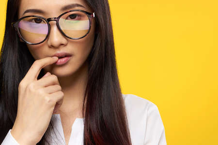 woman asian appearance elegant style glasses hand near face yellow background