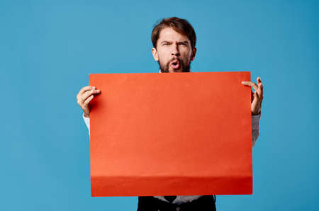 emotional man holding red banner communication advertising isolated blue backgroundの写真素材