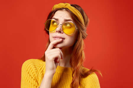 emotional woman wearing glasses yellow sweater casual clothing hippie studio red backgroundの写真素材