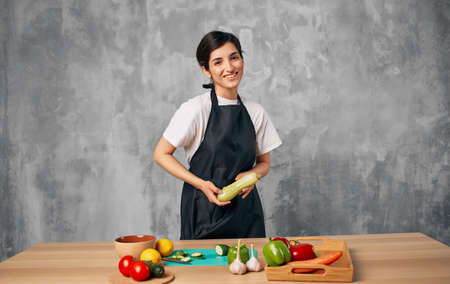 Woman cook black apron slicing vegetables cutting board kitchen cooking foodの写真素材