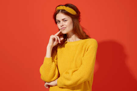 pretty emotional woman holding her hair Yellow sweater fashion red backgroundの写真素材