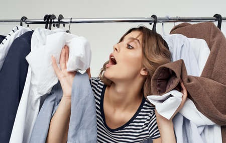 Happy woman peeking out from behind clothes in dressing room shopping youthの写真素材