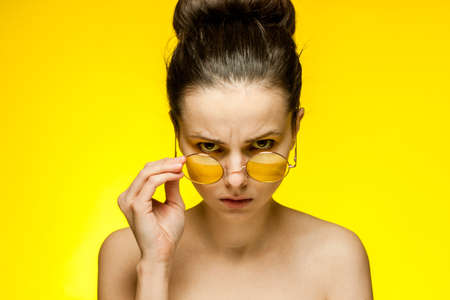 pretty woman with bare shoulders yellow glasses emotions cropped viewの写真素材