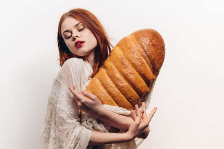 beautiful woman hugging loaf with her hands makeup transparent fabric on her shouldersの写真素材