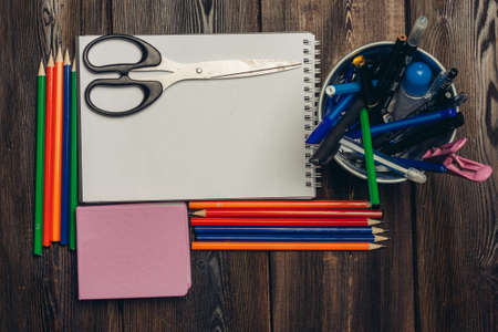 stationery on a wooden table open notepad scissors colored pencils noteの写真素材