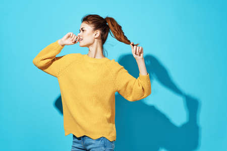 pretty woman in yellow sweater attractive look emotions close-up blue backgroundの写真素材