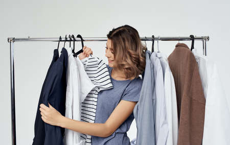 woman examines striped t-shirt near clothes in wardrobe shoppingの写真素材