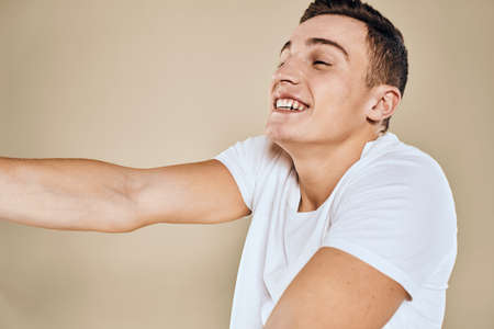 Emotional man white t-shirt gestures with hands lifestyle beige backgroundの写真素材