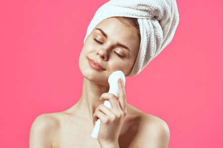 woman with towel on head naked shoulders cosmetology facial massagerの写真素材