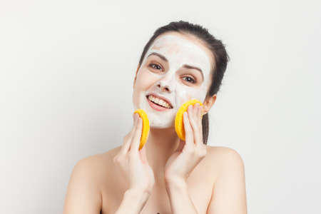woman with bare keys cream mask scrub sponges in handsの写真素材