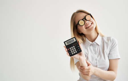 blonde in glasses with a calculator in the hands of cryptocurrency Bitcoin financeの写真素材
