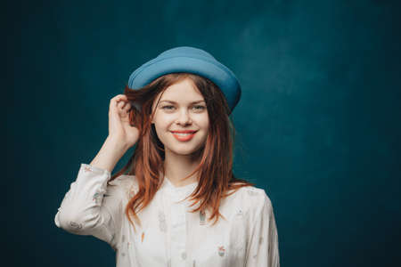 emotional woman in blue hat gesturing with hands red hair blonde sweater