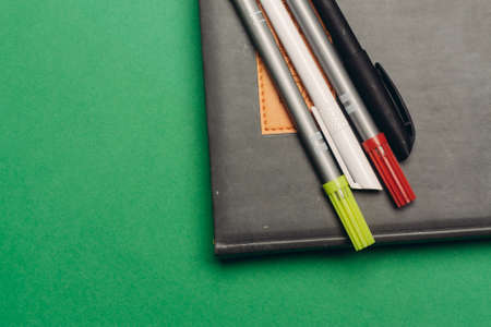 notepad markers pens office supplies and yellow green backgroundの写真素材