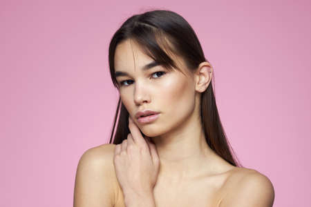Woman with bare shoulders hair care makeup clean skin pink backgroundの写真素材