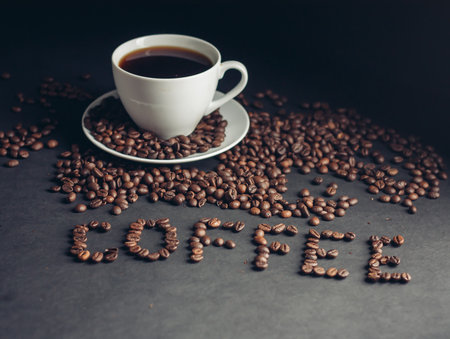 cup with a fragrant drink on a dark background heart of coffee beans white saucerの写真素材