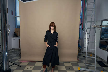 Fashionable woman studio black coat red lips Indoor paper background.