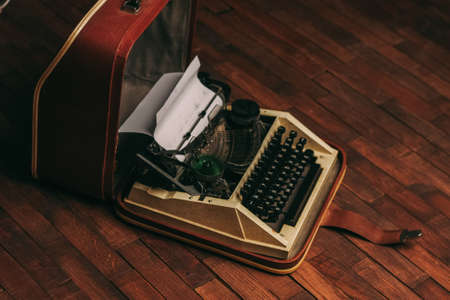 vintage typewriter with white paper stands on the floor indoors
