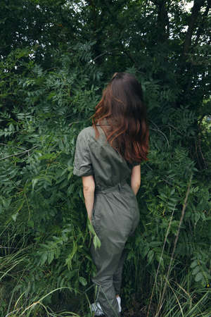 Woman in forest in green overalls in the park in nature nature travelの写真素材