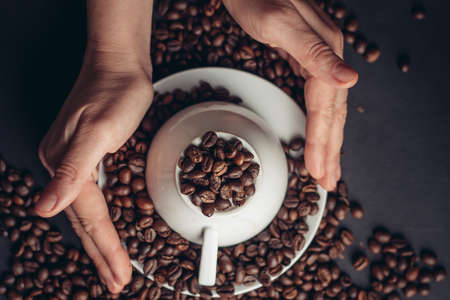 inverted white cup on a saucer and coffee beans on a gray table close-ups top viewの写真素材
